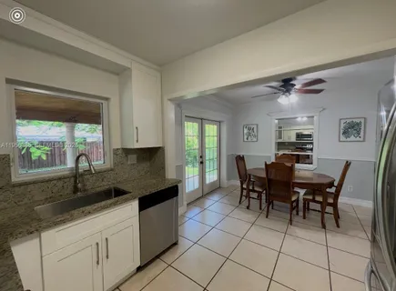 a kitchen with granite countertop a sink dining table and chairs