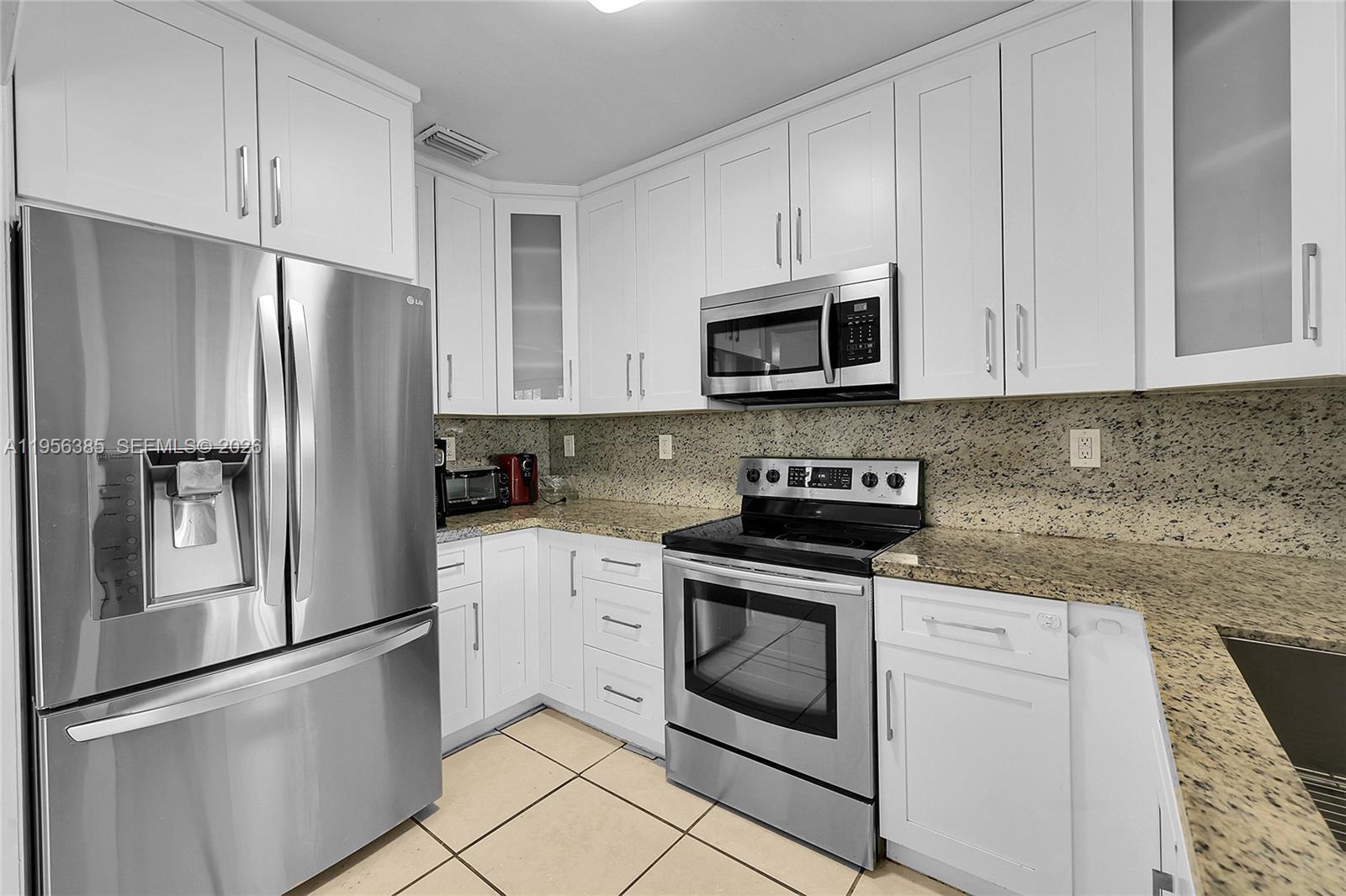 3614 Southwest 58th Avenue Miami, FL 33155 - Photo 19 of 27 a kitchen with stainless steel appliances granite countertop white cabinets a refrigerator and a stove a refrigerator with white cabinets