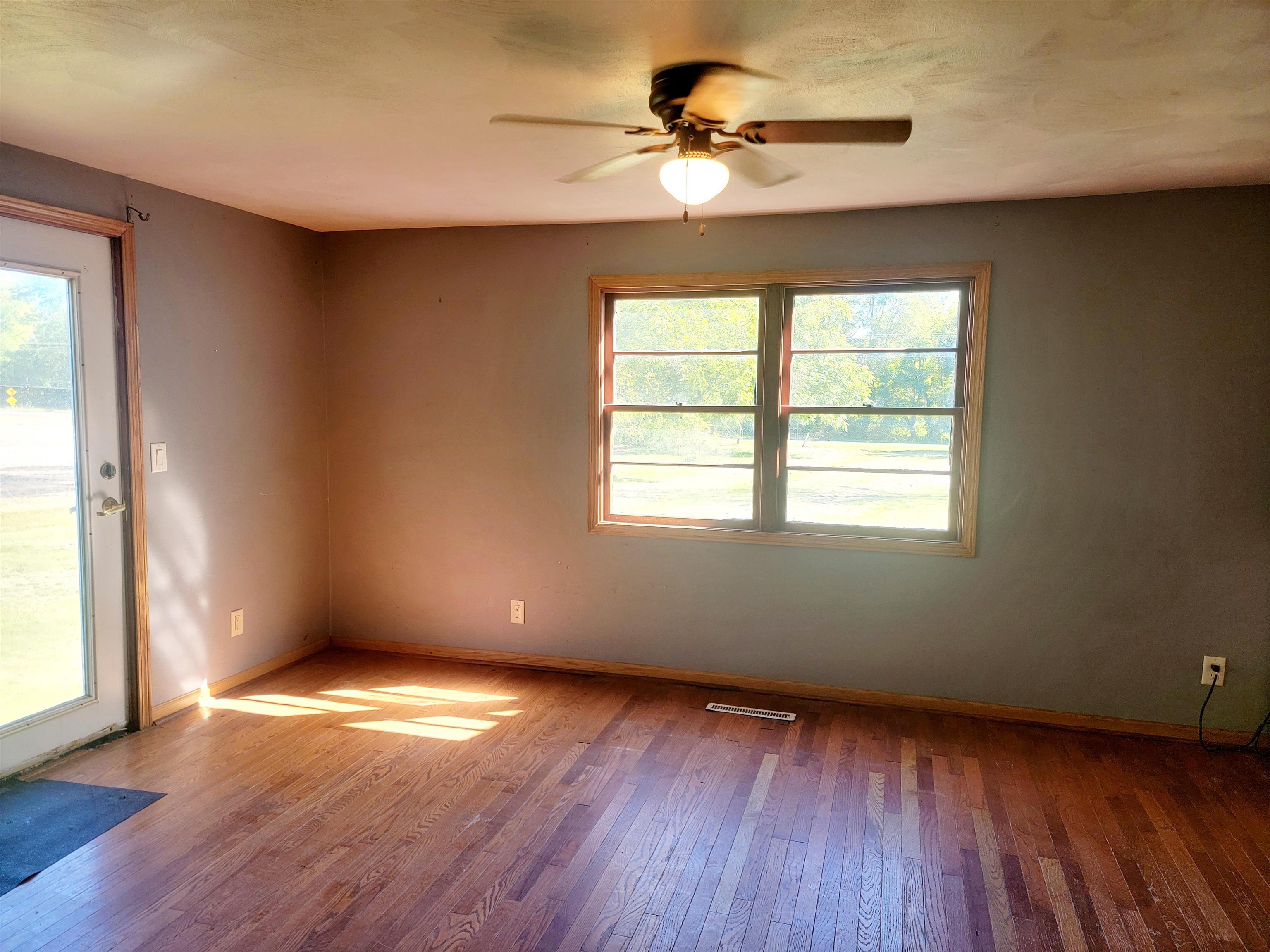8014 South Creek Road Beloit, WI 53511 - Photo 22 of 39 an empty room with wooden floor chandelier fan and windows