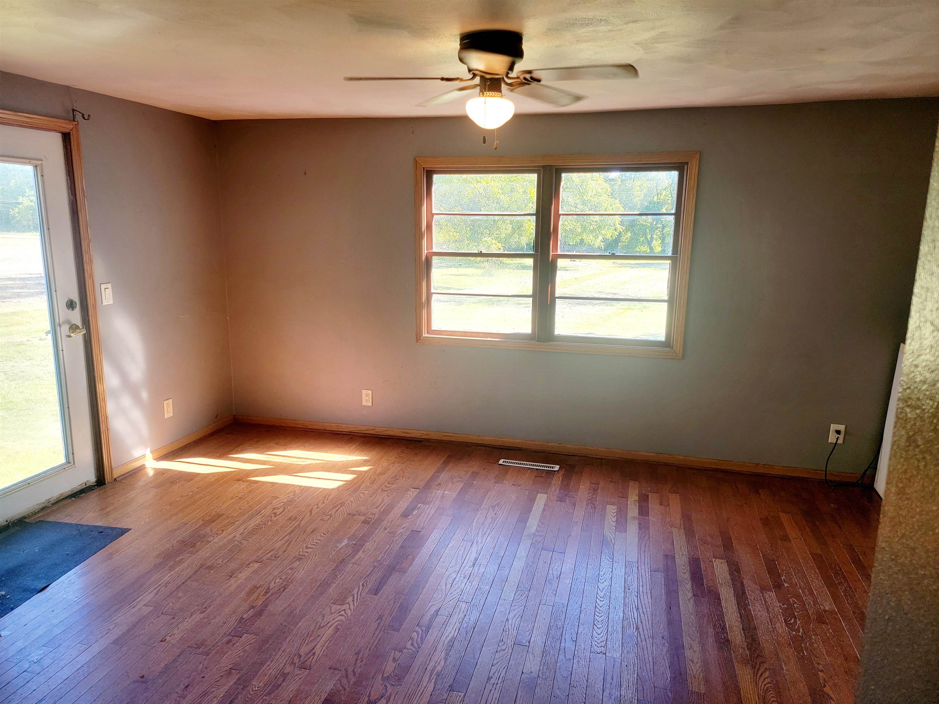8014 South Creek Road Beloit, WI 53511 - Photo 23 of 39 an empty room with wooden floor chandelier fan and windows