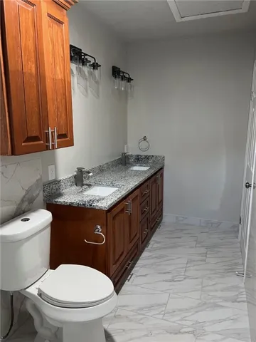 a bathroom with a granite countertop toilet sink and mirror