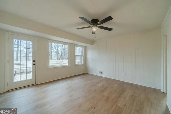 a view of an empty room with wooden floor and a window