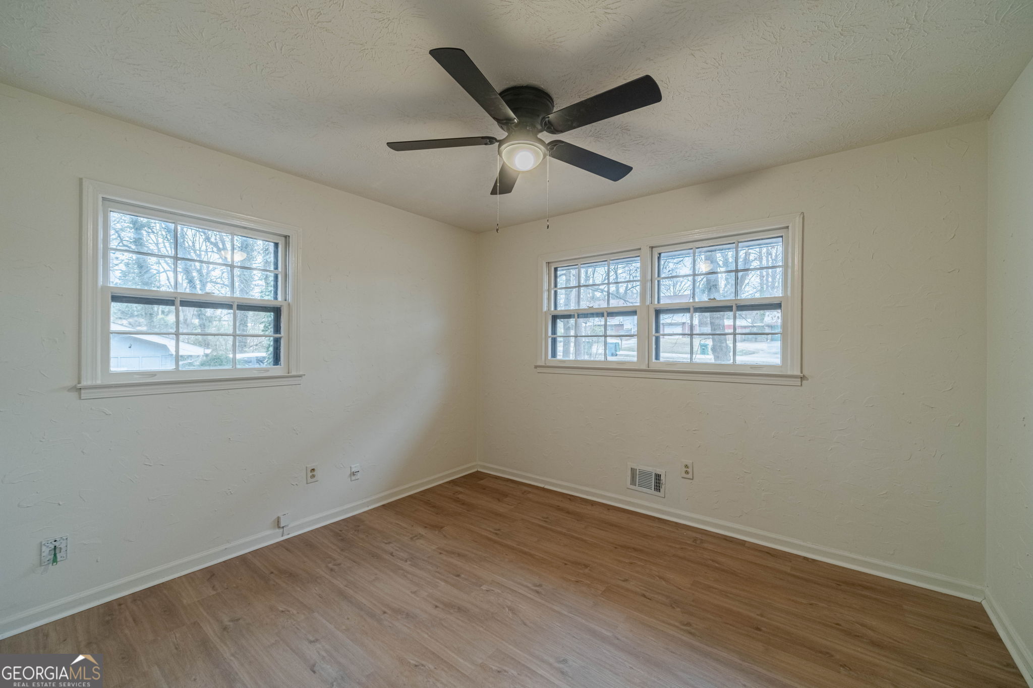 1678 Pounds Road Southwest Stone Mountain, GA 30087 - Photo 19 of 30 an empty room with wooden floor ceiling fan and windows