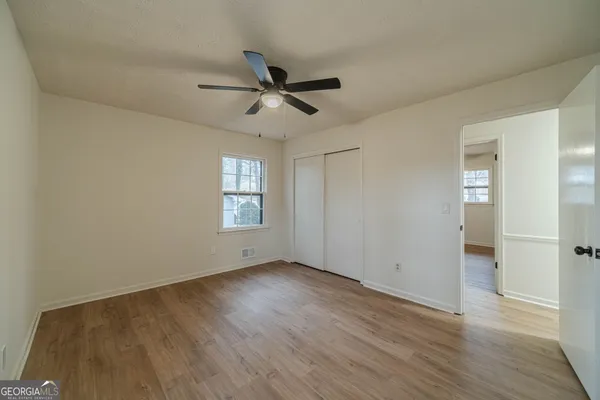 a view of empty room with wooden floor and fan