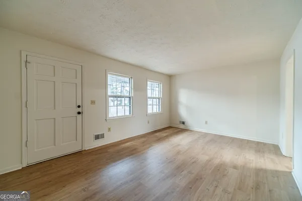 a view of an empty room with wooden floor and a window