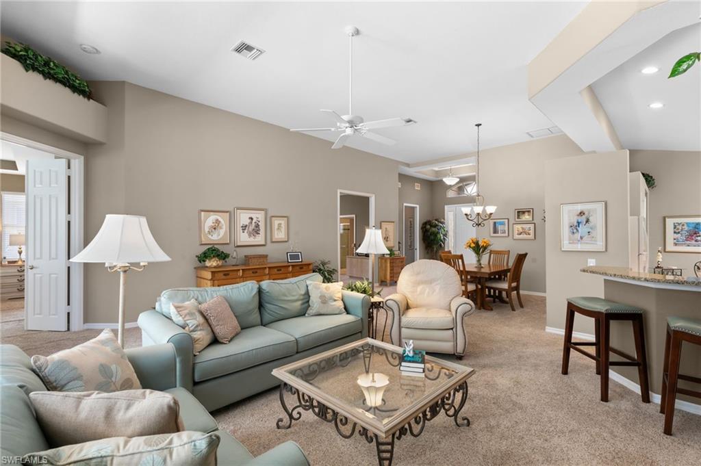 1717 Winding Oaks Way Naples, FL 34109 - Photo 12 of 35 Living room with light colored carpet and ceiling fan with notable chandelier