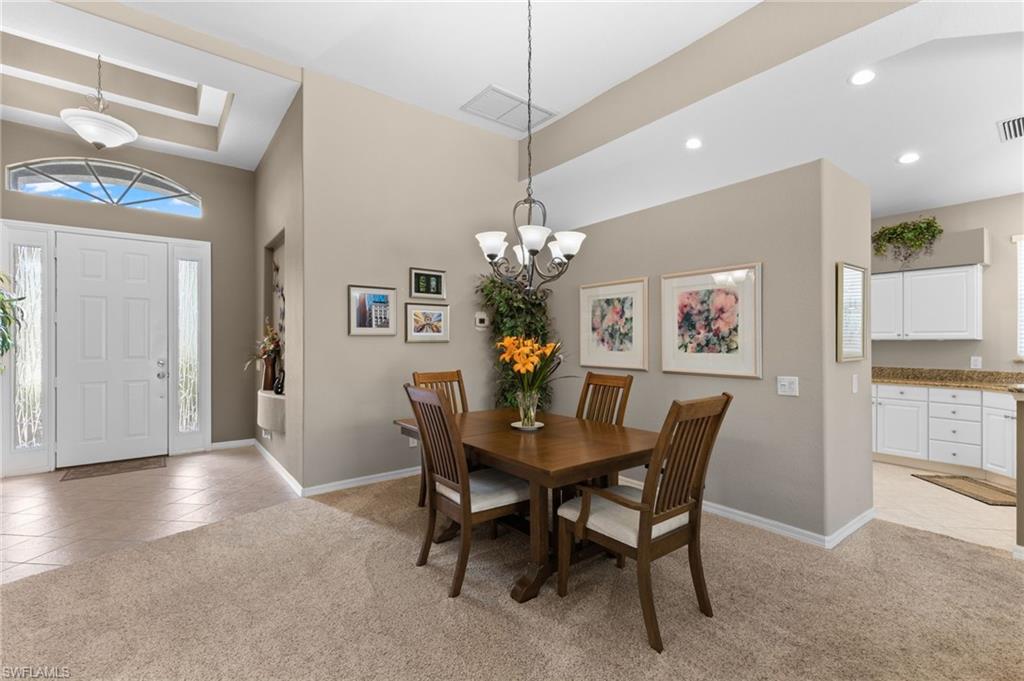 1717 Winding Oaks Way Naples, FL 34109 - Photo 5 of 35 Carpeted dining room featuring a raised ceiling and an inviting chandelier