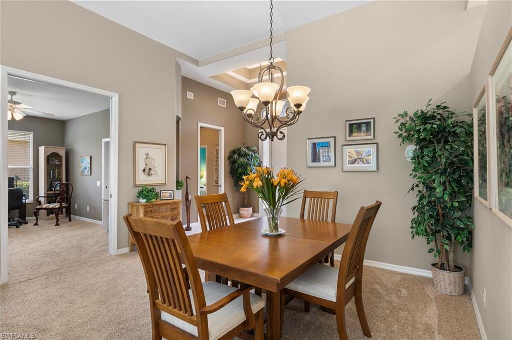 1717 Winding Oaks Way Naples, FL 34109 - Photo 6 of 35 Carpeted dining area with a high ceiling, ceiling fan with notable chandelier, and a tray ceiling