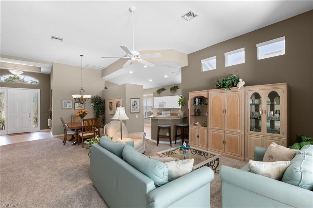 1717 Winding Oaks Way Naples, FL 34109 - Photo 8 of 35 Living room with a high ceiling, ceiling fan with notable chandelier, and light carpet