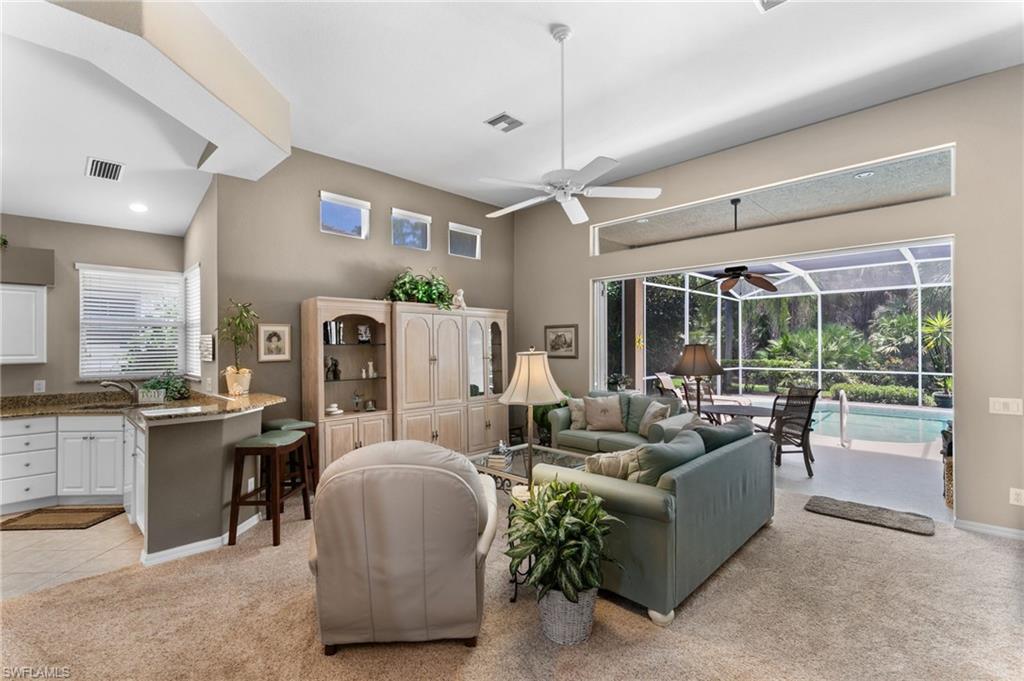 1717 Winding Oaks Way Naples, FL 34109 - Photo 9 of 35 Living room featuring ceiling fan, a healthy amount of sunlight, and light colored carpet