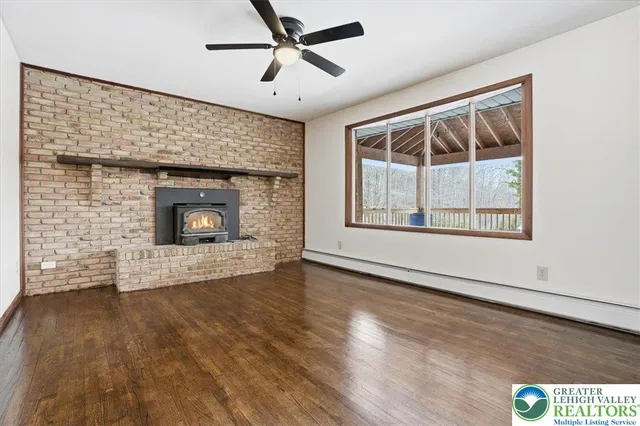 a view of an empty room with wooden floor and a fireplace