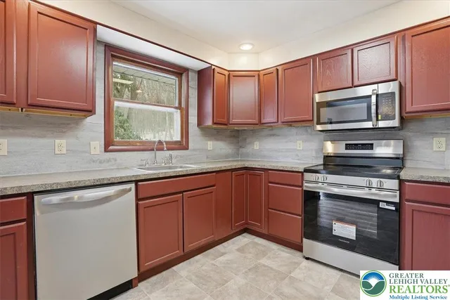 a kitchen with stainless steel appliances granite countertop a stove a sink and a microwave