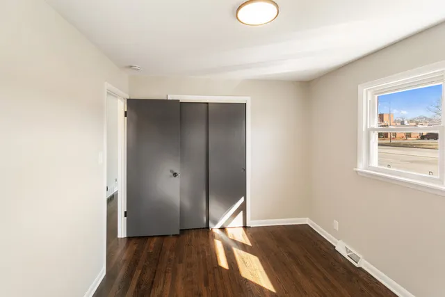 a view of an empty room with wooden floor and a window