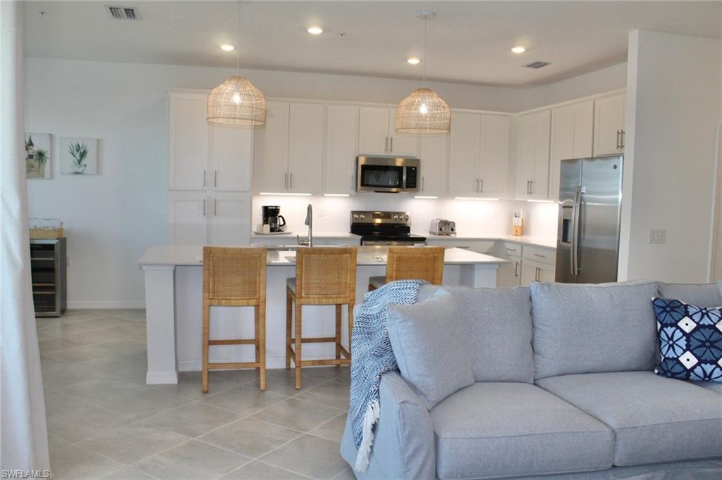 15405 Grn Acrs Avenue, Unit 2341 Babcock Ranch, FL 33982 - Photo 4 of 28 a living room with stainless steel appliances furniture a flat screen tv and kitchen view