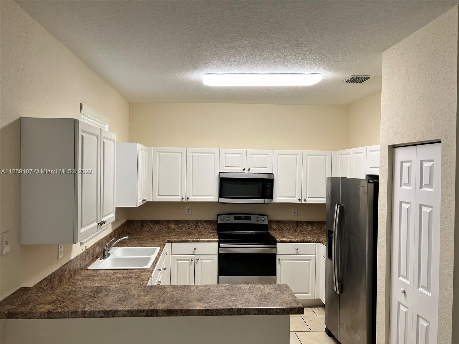 Three Lakes Miami, FL 33186 - Photo 13 of 23 a kitchen with a refrigerator and a stove top oven