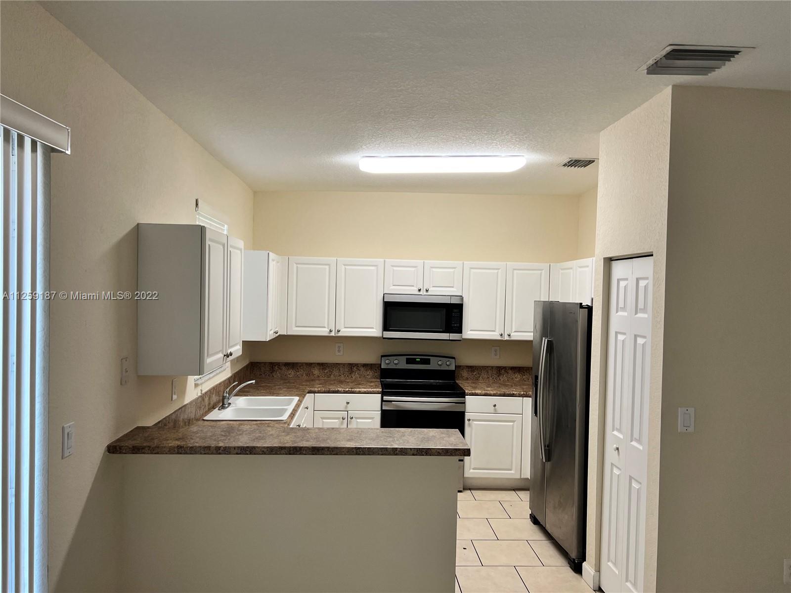 Three Lakes Miami, FL 33186 - Photo 14 of 23 a kitchen with a refrigerator and a stove top oven