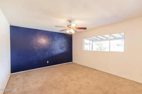 an empty room with a window and a fan