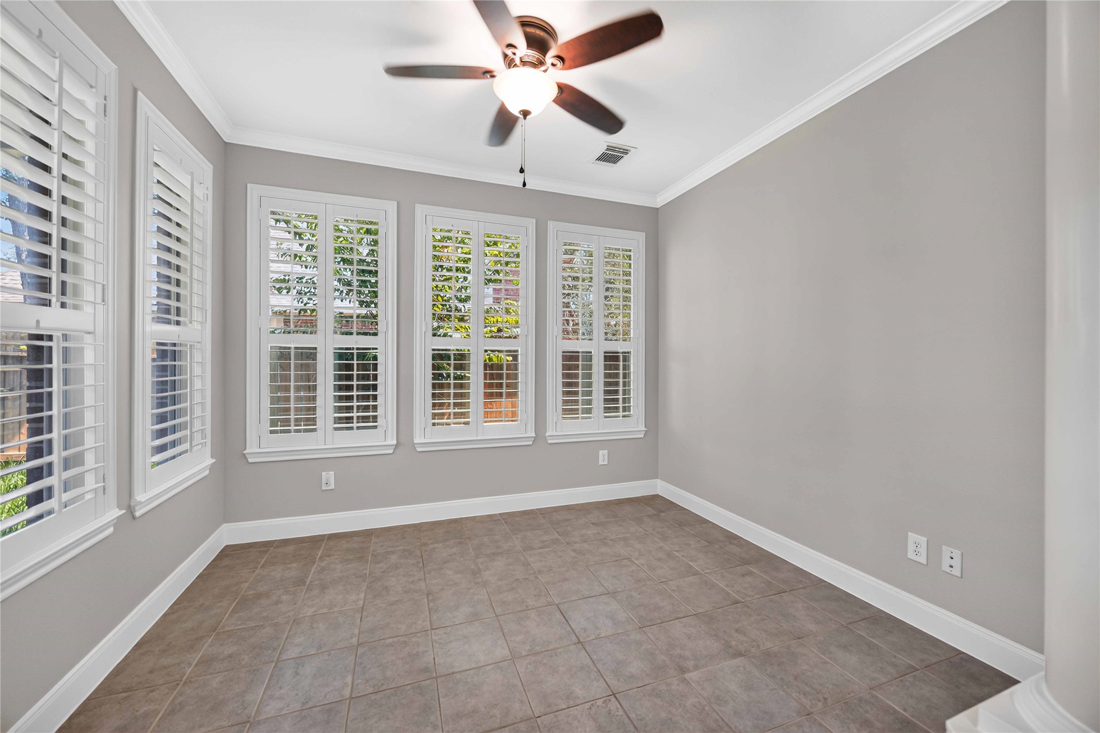 3303 Raleigh Row Missouri City, TX 77459 - Photo 21 of 50 Bright Sunroom with large windows, elegant shutters, and neutral tile flooring, complemented by a ceiling fan for comfort.