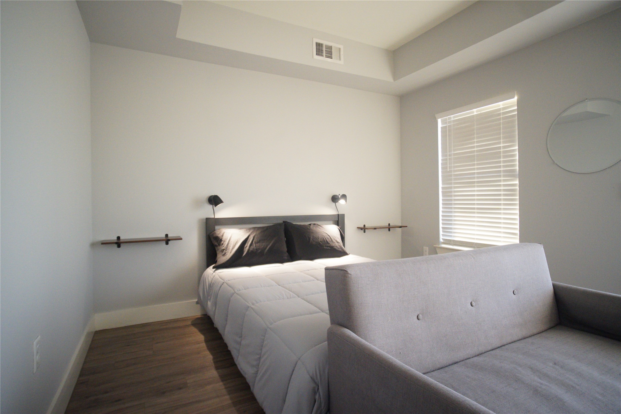6444 Burnet Road, Unit 305 Austin, TX 78757 - Photo 8 of 15 Bright bedroom with warm flooring, natural light, and a flexible layout for sleeping and lounging.