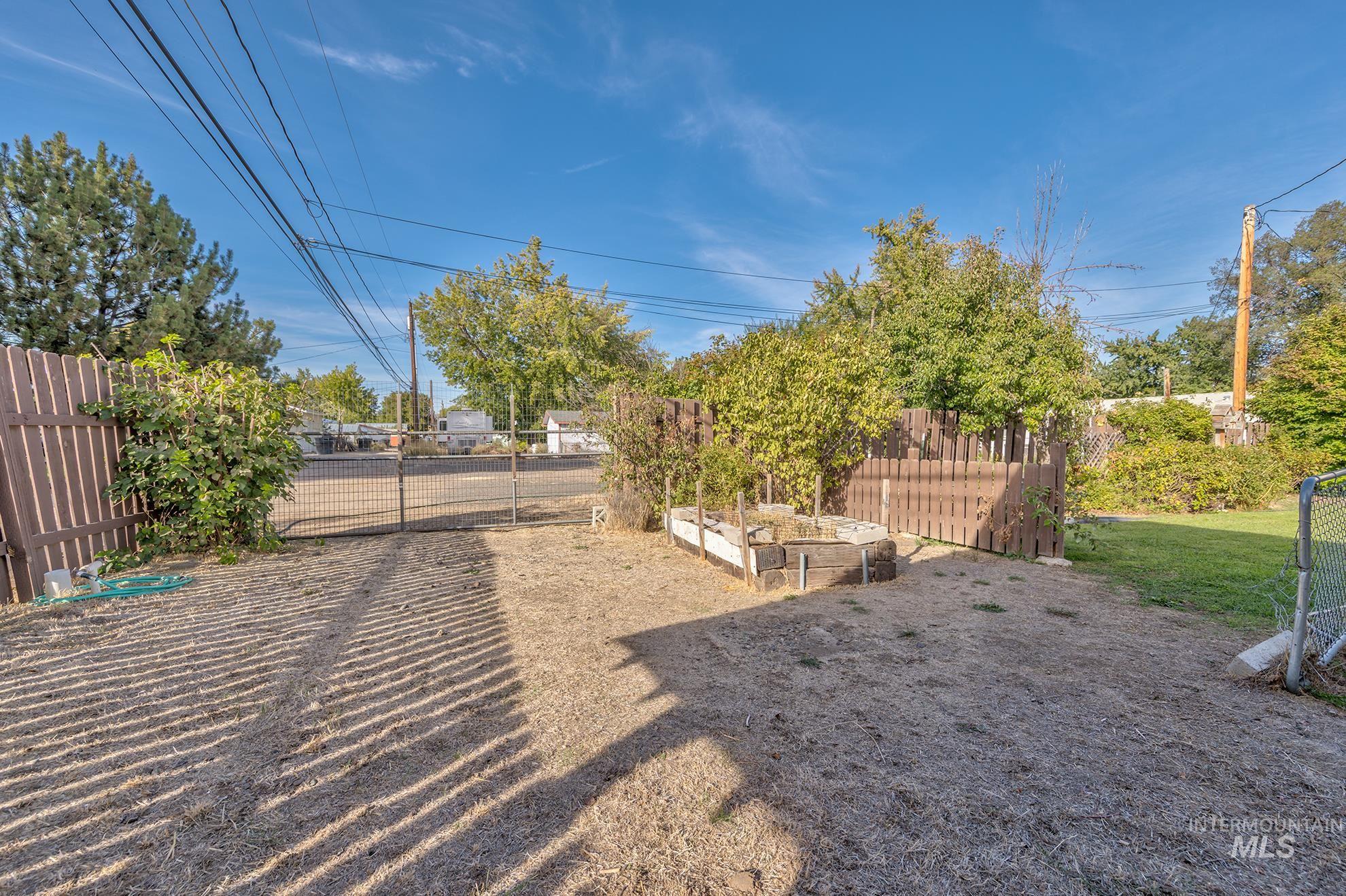 340 Pioneer Road Weiser, ID 83672 - Photo 39 of 44 Fenced backyard with a metal gate and raised garden beds