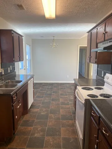 a kitchen with stainless steel appliances granite countertop a stove top oven a sink a counter space and cabinets