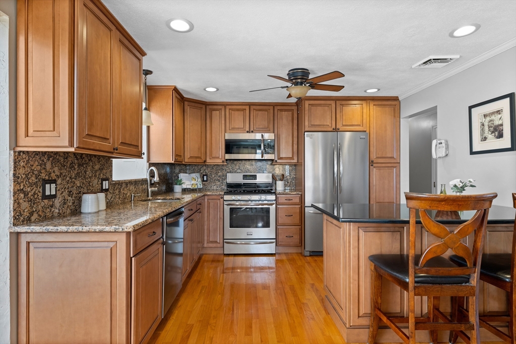 11 Clearview Road Stoneham, MA 02180 - Photo 12 of 42 a kitchen with stainless steel appliances granite countertop a refrigerator a stove a sink dishwasher and wooden cabinets with wooden floor