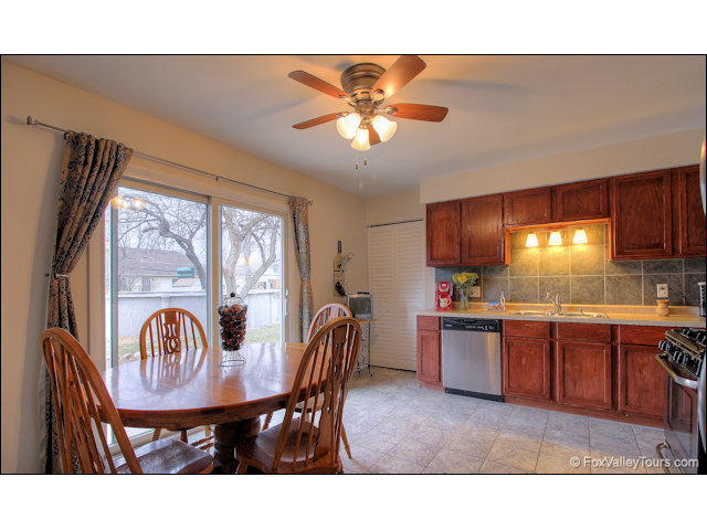 56 Sheffield Road Montgomery, IL 60538 - Photo 9 of 18 a open kitchen with stainless steel appliances granite countertop a sink a stove a dining table and chairs