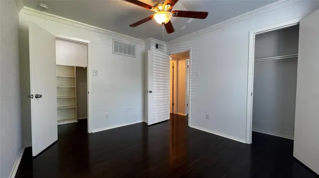 an empty room with wooden floor closet and windows