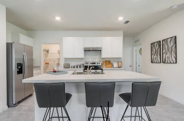 a kitchen with stainless steel appliances kitchen island granite countertop a dining table and chairs