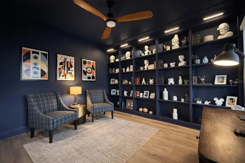 a living room with furniture a piano and a bookshelf