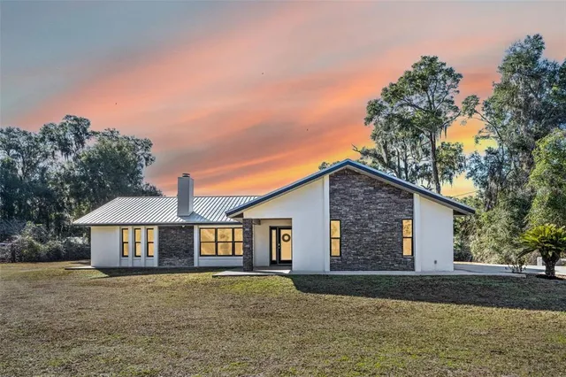 a front view of a house with yard and trees