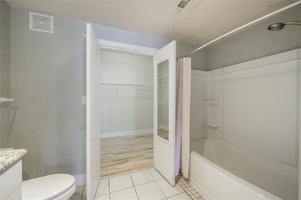 4414 Cedar Springs Road, Unit 214 Dallas, TX 75219 - Photo 20 of 29 Full bath with light tile patterned floors, vanity, a spacious closet, and shower / bath combination with curtain