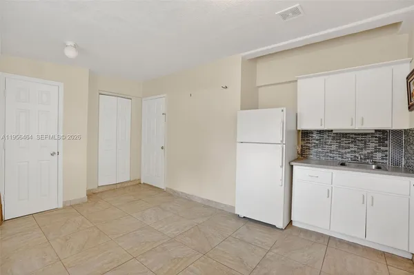 a kitchen with white cabinets and refrigerator