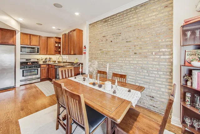 a dining room with stainless steel appliances kitchen island granite countertop a table chairs and a refrigerator