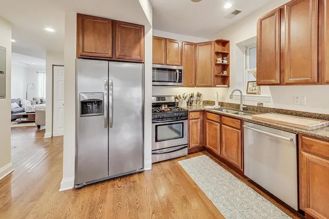 a kitchen with stainless steel appliances granite countertop a refrigerator a sink dishwasher a stove with wooden cabinets and floor