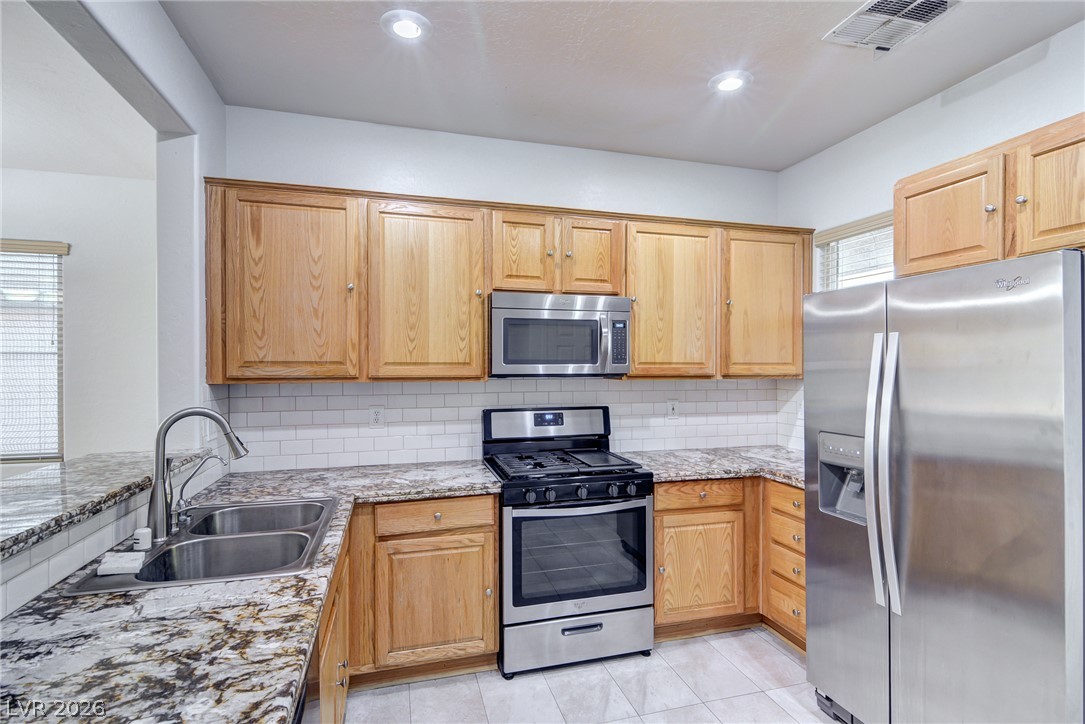 2339 Tranquil Moon Street Henderson, NV 89044 - Photo 2 of 15 Gleaming stone countertops and classic wood cabinetry anchor this functional workspace.