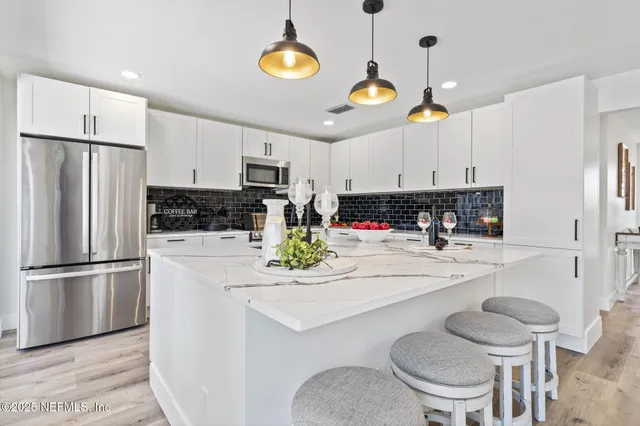 a kitchen with stainless steel appliances granite countertop a stove a refrigerator a microwave a sink a dining table and chairs with wooden floor