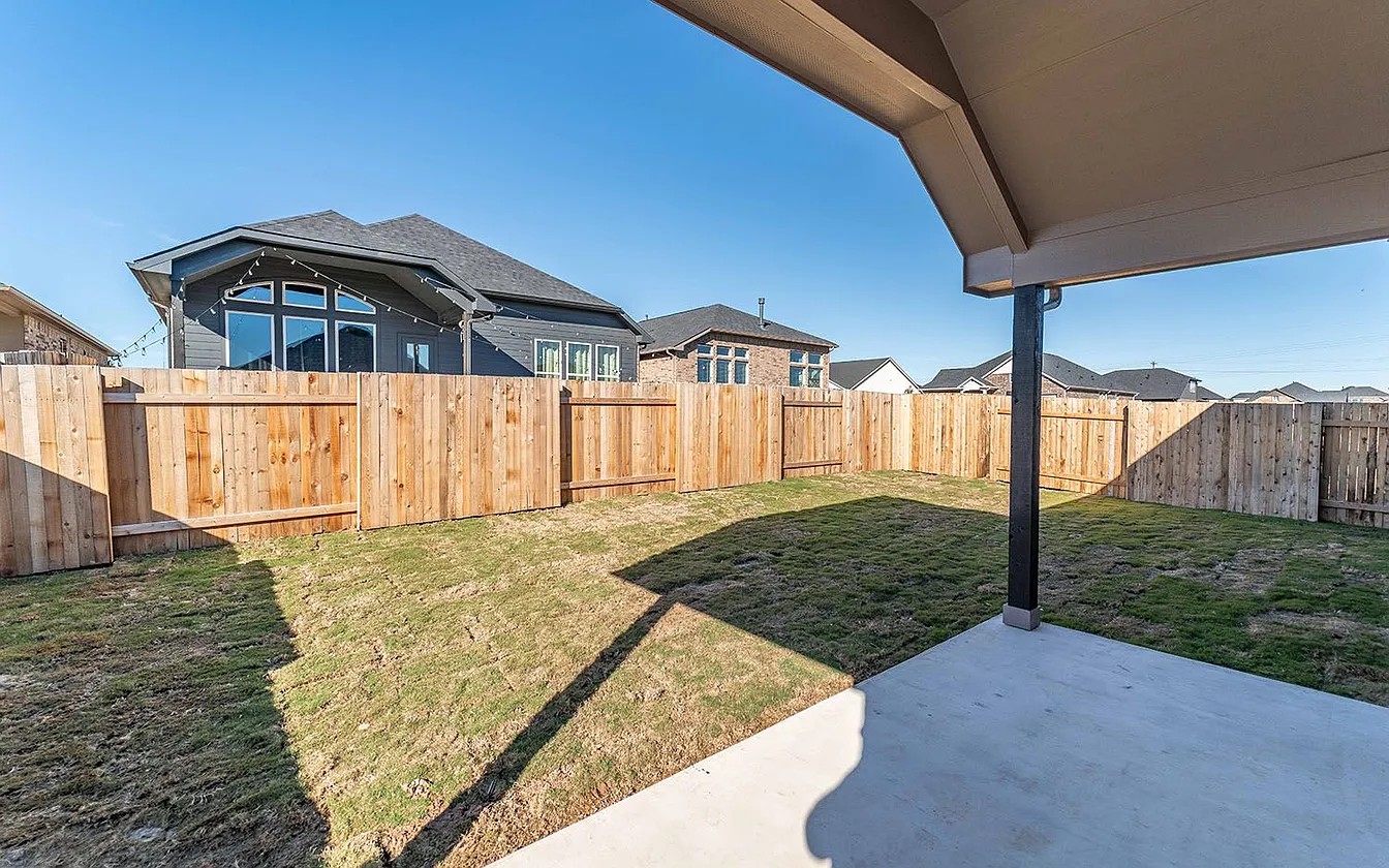 450 Durian Loop Buda, TX 78610 - Photo 7 of 17 A spacious backyard awaits, complete with a covered patio for outdoor relaxation.