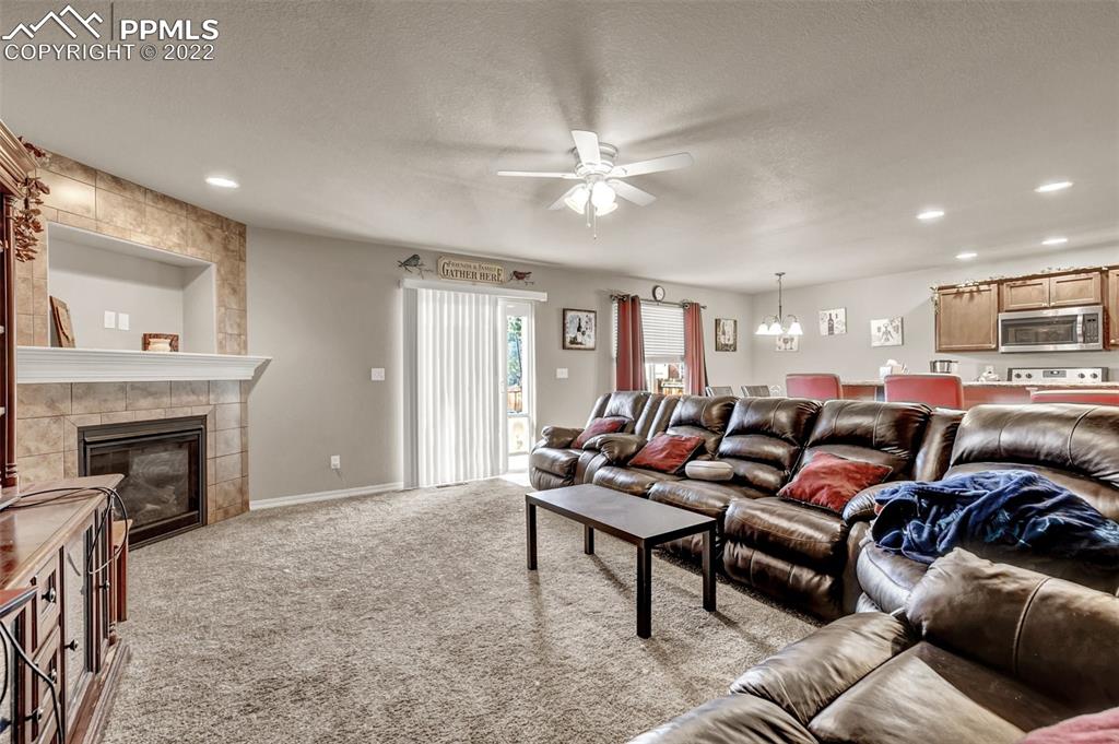 6570 Gelbvieh Road Peyton, CO 80831 - Photo 3 of 38 a living room with furniture a fireplace and a ceiling fan