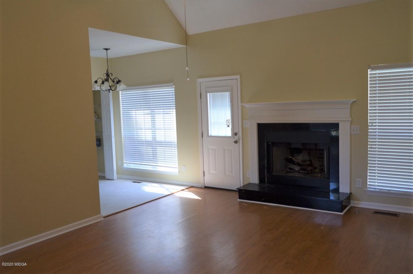 253 Chadwick Circle Macon, GA 31210 - Photo 3 of 19 an empty room with wooden floor fireplace and windows