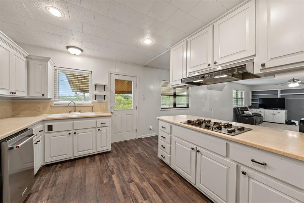 608 West Spring Street West, TX 76691 - Photo 10 of 27 a kitchen with stainless steel appliances granite countertop a stove a sink dishwasher and white cabinets with wooden floor