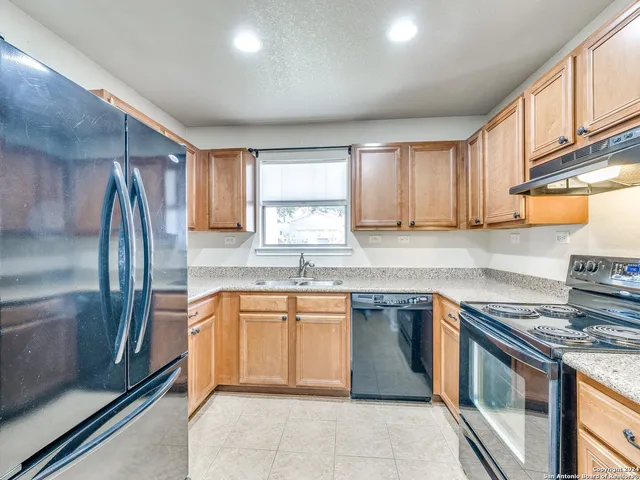 a kitchen with stainless steel appliances granite countertop a sink stove refrigerator and cabinets