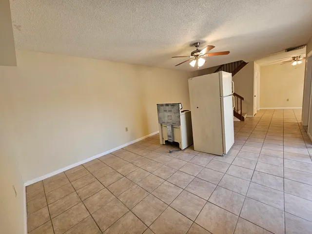 a view of a livingroom with chandelier fan and kitchen view