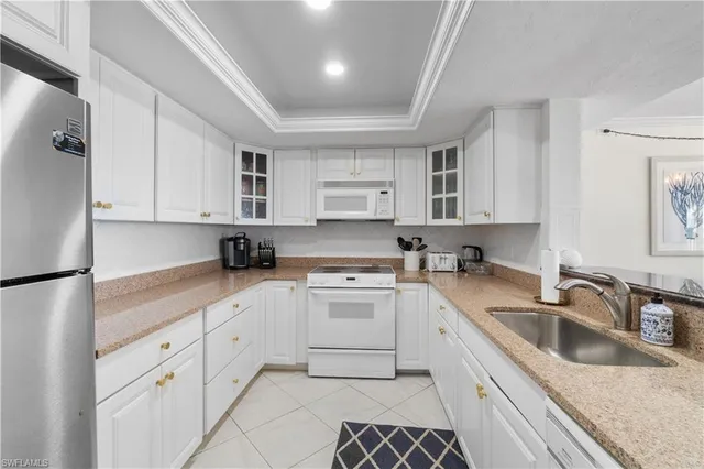 a kitchen with granite countertop white cabinets white appliances and sink