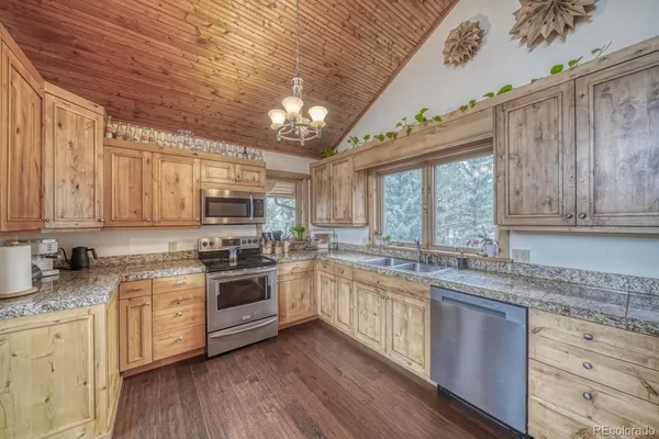 a kitchen with stainless steel appliances granite countertop a stove a sink dishwasher and white cabinets with wooden floor
