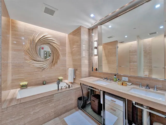 a spacious bathroom with a granite countertop double vanity sink a mirror and a bathtub