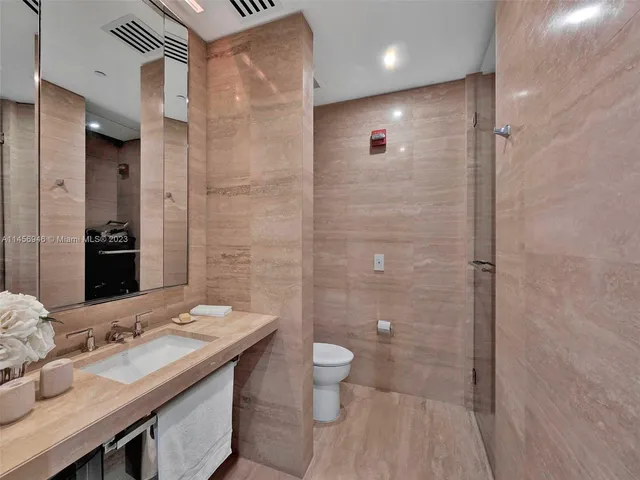 a bathroom with a granite countertop sink a toilet a mirror and shower