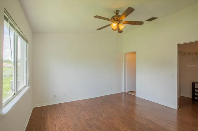 an empty room with wooden floor and windows