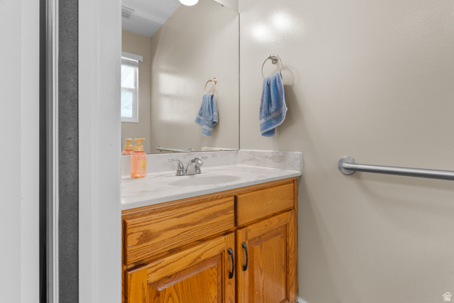 5727 South 3550th Street West Roy, UT 84067 - Photo 24 of 49 Half bath, featuring wood-finish cabinetry, a built-in sink, and a light-toned countertop