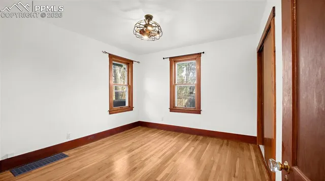 a view of an empty room with a window and wooden floor